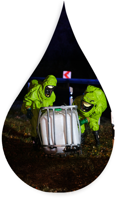 Two people in green suits and masks working on a container.